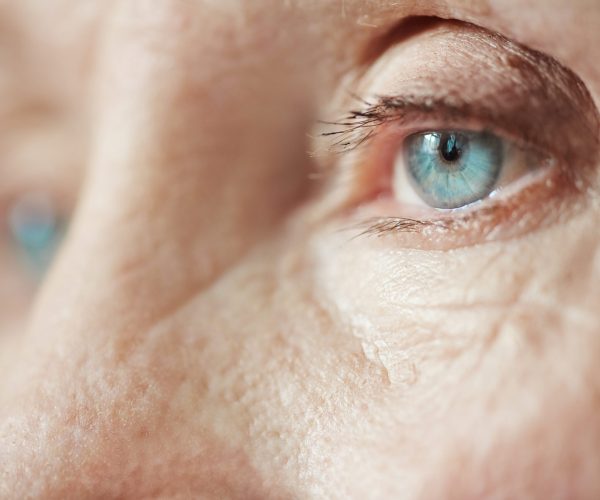 Extreme close-up shot of sad blue eyes on wrinkled female face looking into the distance